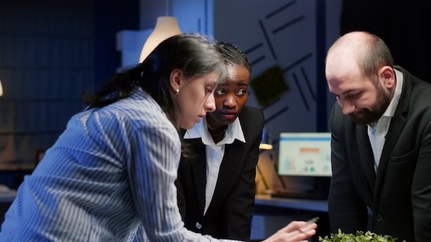 A group of diverse professionals gathered around a table, intensely discussing and analyzing data on a large screen, signifying collaborative problem-solving and strategic decision-making.