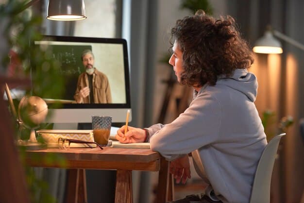 A remote employee participating in a virtual training session on their laptop, highlighting the importance of continuous learning and development in a remote work environment. The employee is taking notes with a focused expression.