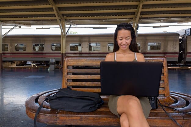 A digital nomad working on their laptop at a table in a stylish coworking space in Austin, Texas. A scooter rental dock is visible just outside the window.