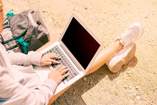 A digital nomad setting up a portable monitor next to their laptop at a desk in a co-working space. They are connecting the monitor with a USB-C cable.