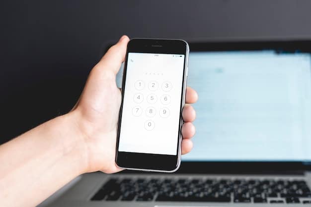 A close-up of a smartphone displaying a one-time password (OTP) for multi-factor authentication, with a laptop in the blurred background.