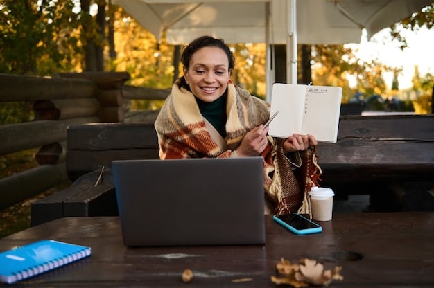 A digital nomad closes her laptop in a shared workspace, signaling the end of her workday. A cup of coffee and a notebook are next to the laptop. She is smiling and relaxed.