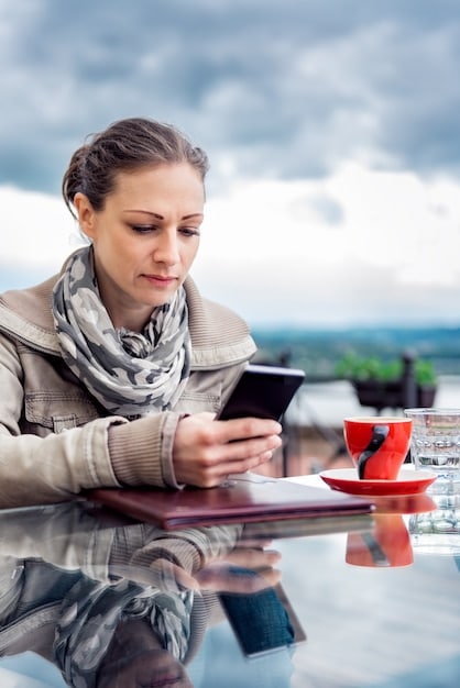 A digital nomad uses a time management app on her smartphone while sitting in a hammock, balancing work efficiency with relaxation. The app shows a visually appealing schedule with allocated time slots.