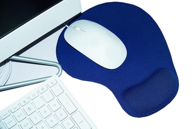 A close-up perspective of an ergonomic keyboard with a gel wrist rest, placed on a clean desk with minimalist accessories. The keyboard is slightly angled, highlighting its ergonomic design, and the wrist rest shows a comfortable, supportive gel material.