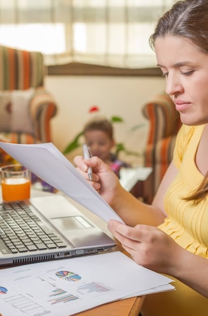 A close-up image of a freelancer using a spreadsheet on their laptop to calculate their estimated quarterly taxes, with various receipts and financial documents scattered around.