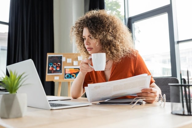 A freelancer sitting at their desk, reviewing insurance policy documents, with a cup of coffee nearby.